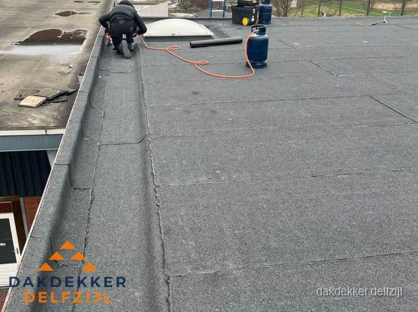 Dakdekker repareert bitumen dakbedekking op groot plat dak in Delfzijl Dakdekker repareert bitumen dakbedekking op groot plat dak in Delfzijl